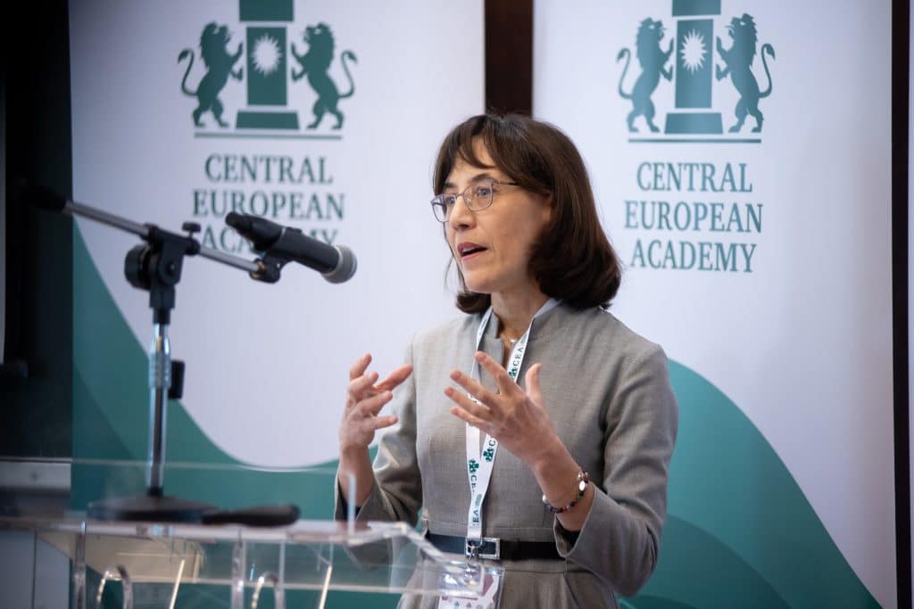 Female speaker smiling while presenting at the conference podium.