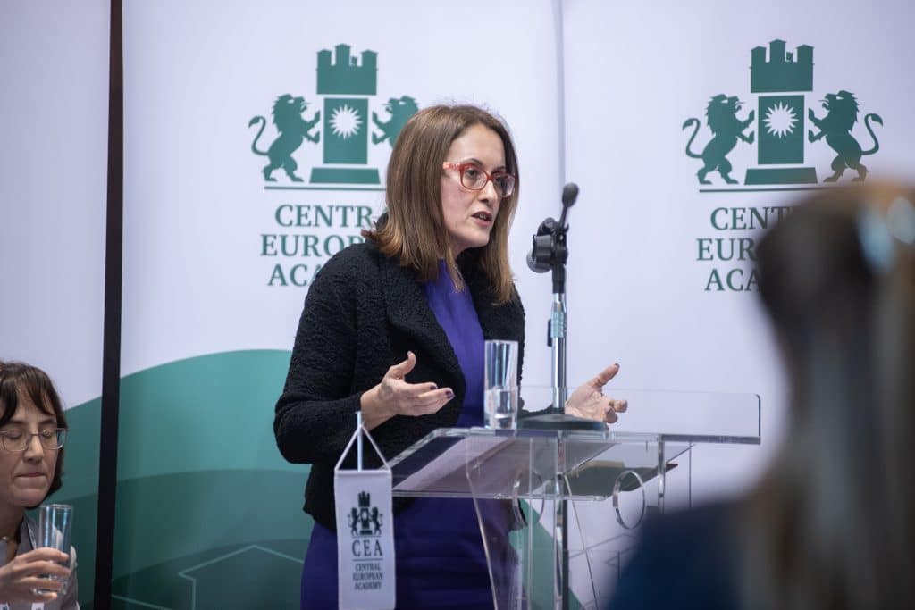 Female speaker smiling while presenting at the conference podium.