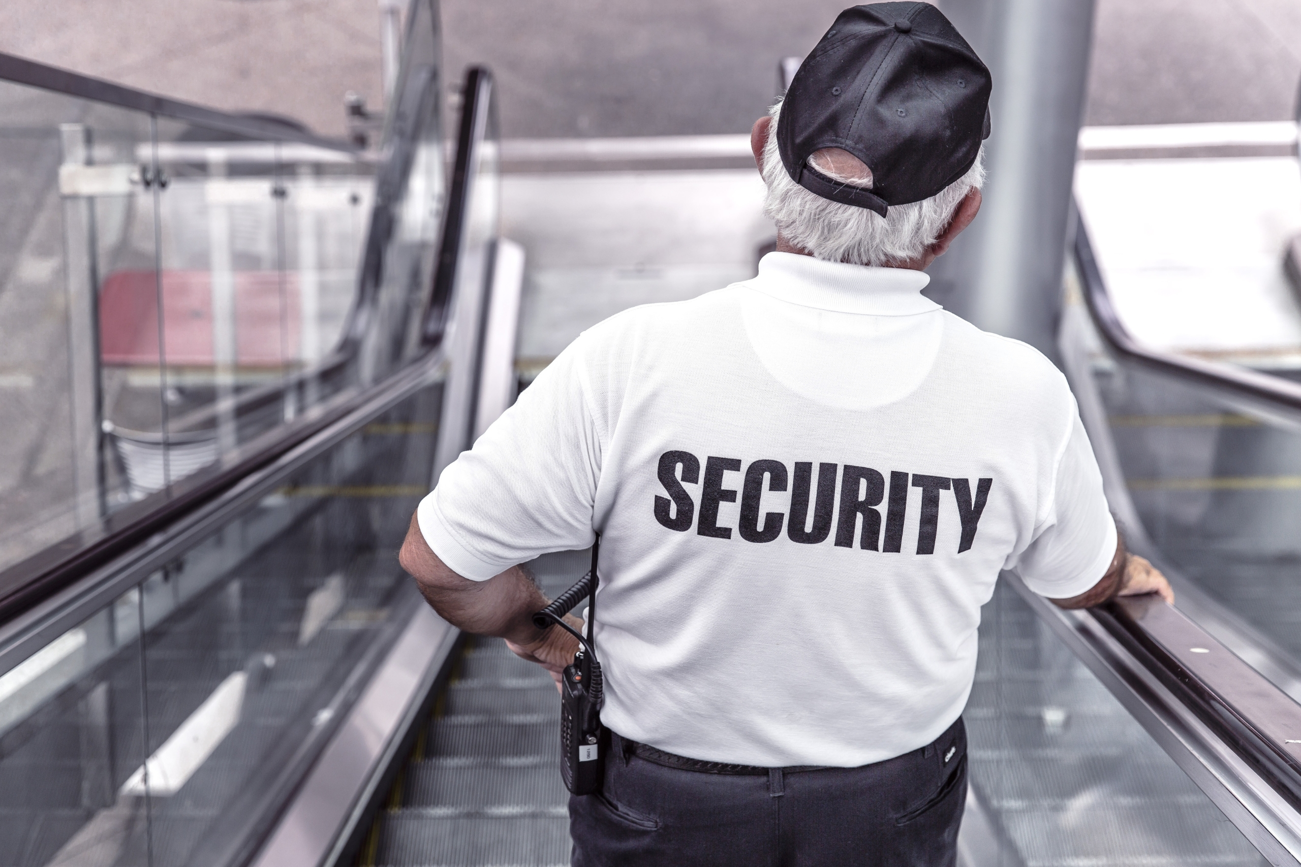Biztonsági őr mozgólépcsőn, SECURITY felirattal a hátán