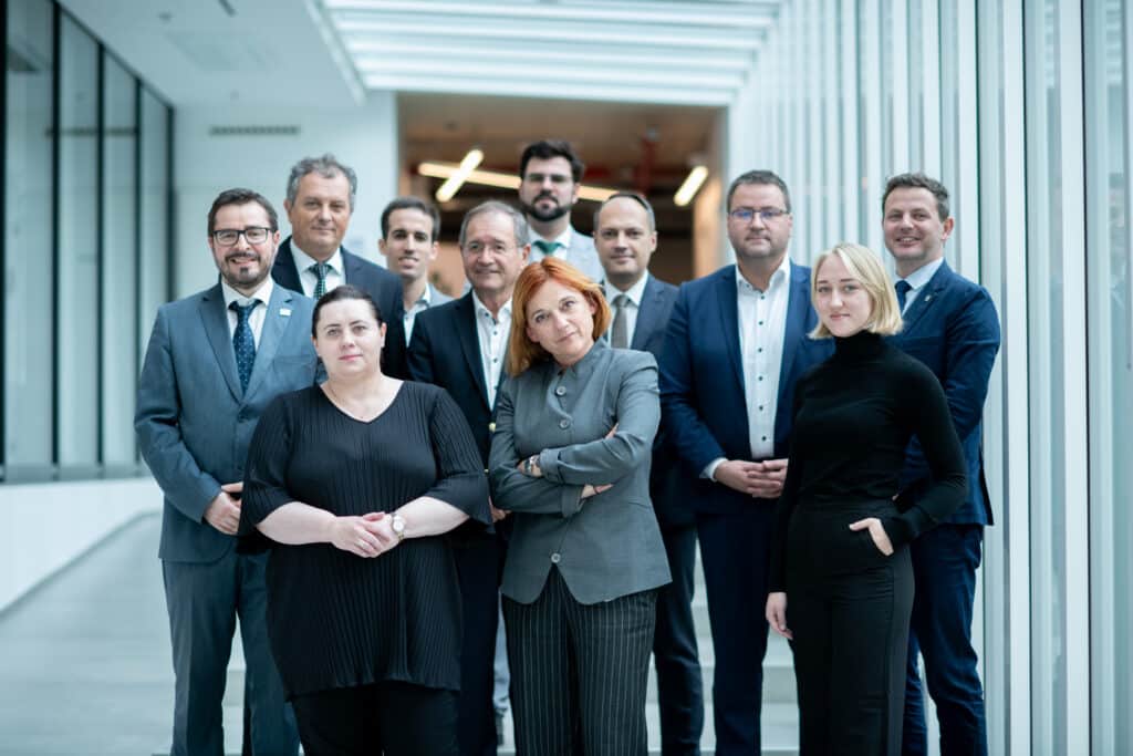 Öltönyös csoportkép a konferencián résztvevőkkel