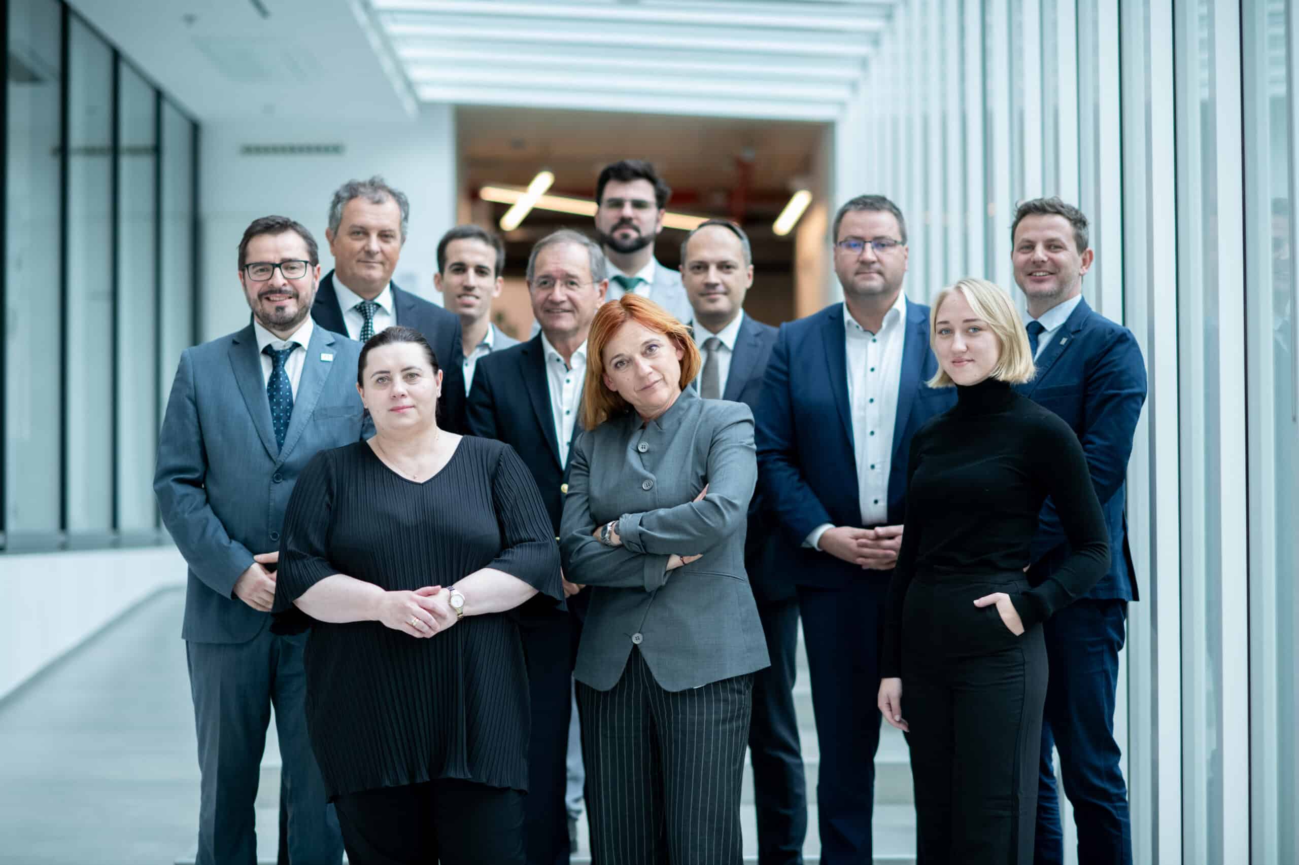 Öltönyös csoportkép a konferencián résztvevőkkel