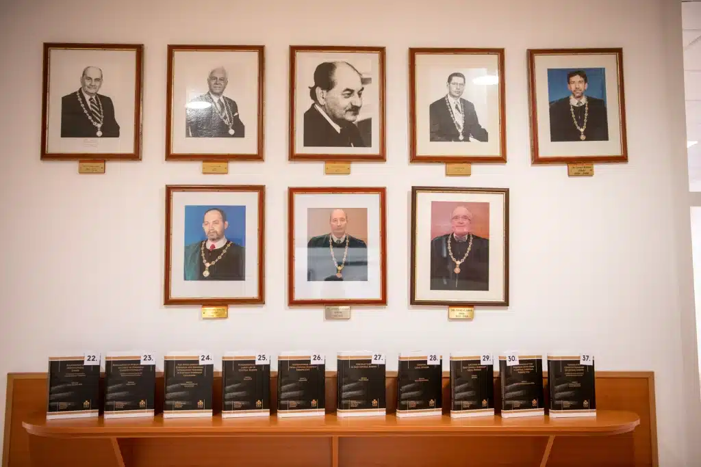Portraits of former deans of the Faculty of Law and legal publications displayed on a shelf
