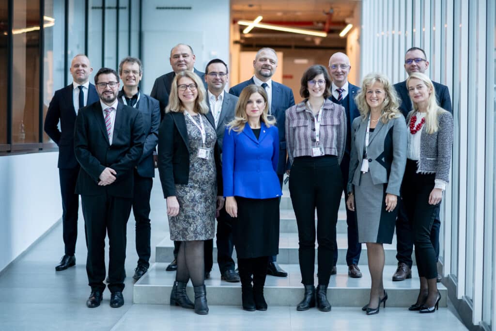 Öltönyös csoportkép a konferencián résztvevőkkel