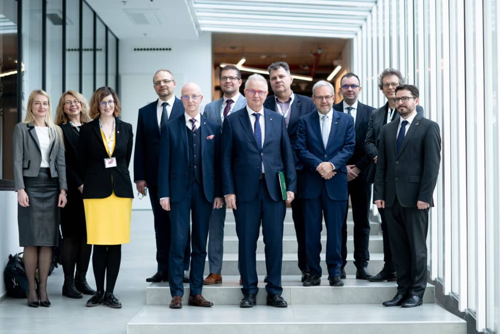 Öltönyös csoportkép a konferencián résztvevőkkel