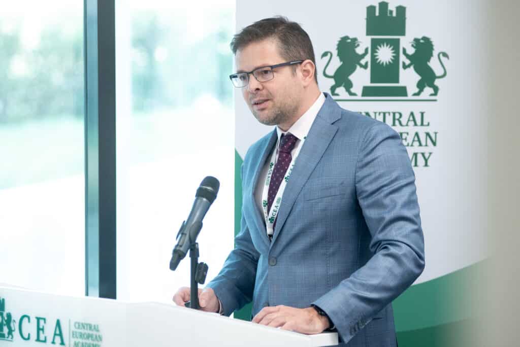 Férfi előadó beszél a CEA pódiumán, hallgatóság előtt