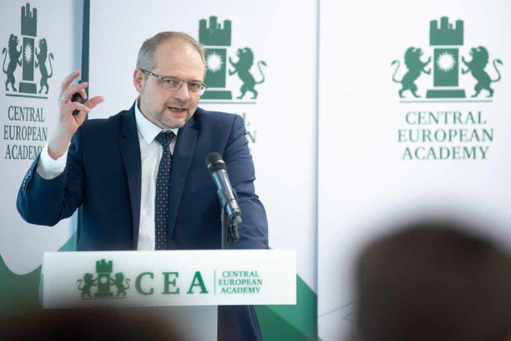 Férfi előadó beszél a CEA pódiumán, hallgatóság előtt