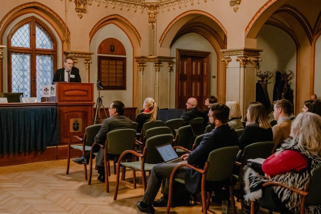 Férfi előadó beszél a CEA pódiumán, hallgatóság előtt