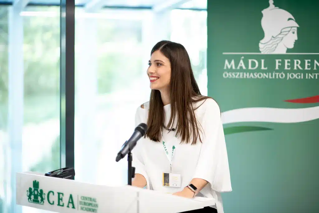Female speaker smiling while presenting at the conference podium.