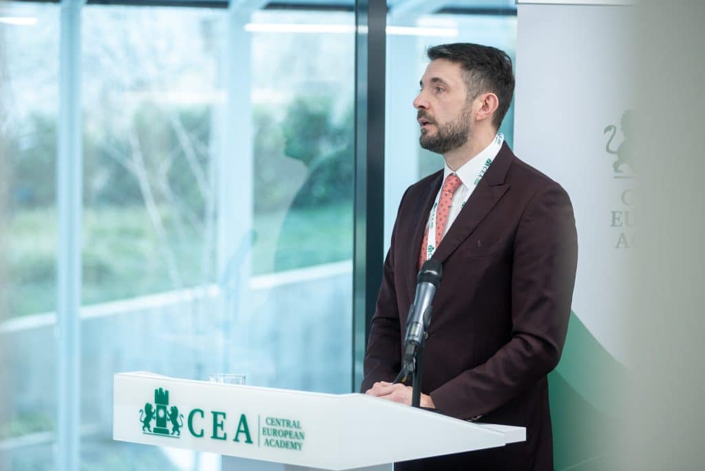 Férfi előadó beszél a CEA pódiumán, hallgatóság előtt