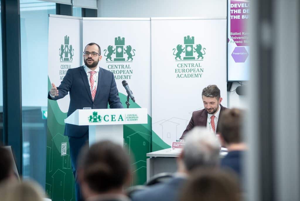 Férfi előadó beszél a CEA pódiumán, hallgatóság előtt