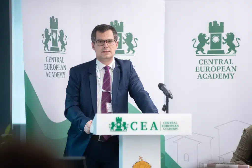 Férfi előadó beszédet tart a CEA logója előtt