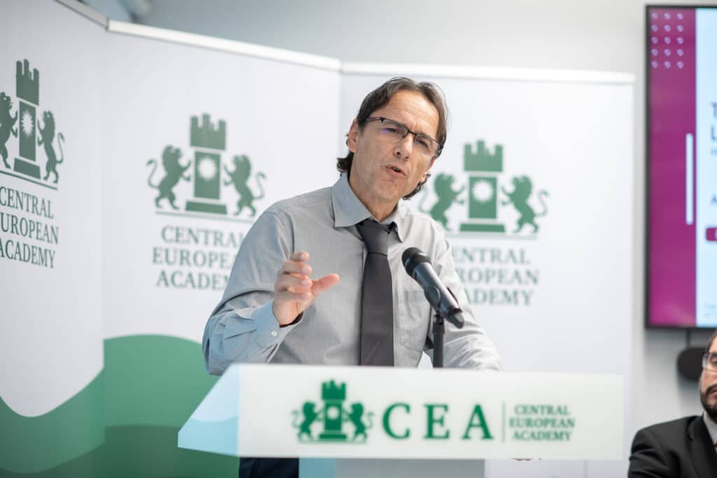 Férfi előadó beszédet tart a Central European Academy logója előtt