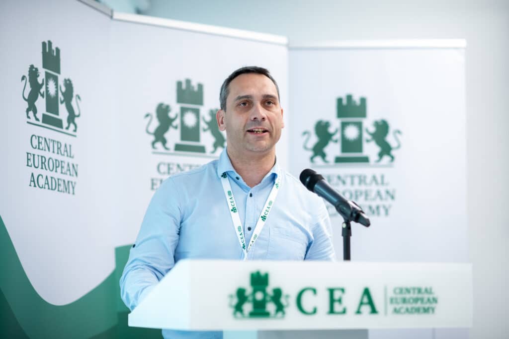 Férfi előadó beszél a CEA pódiumán, hallgatóság előtt

