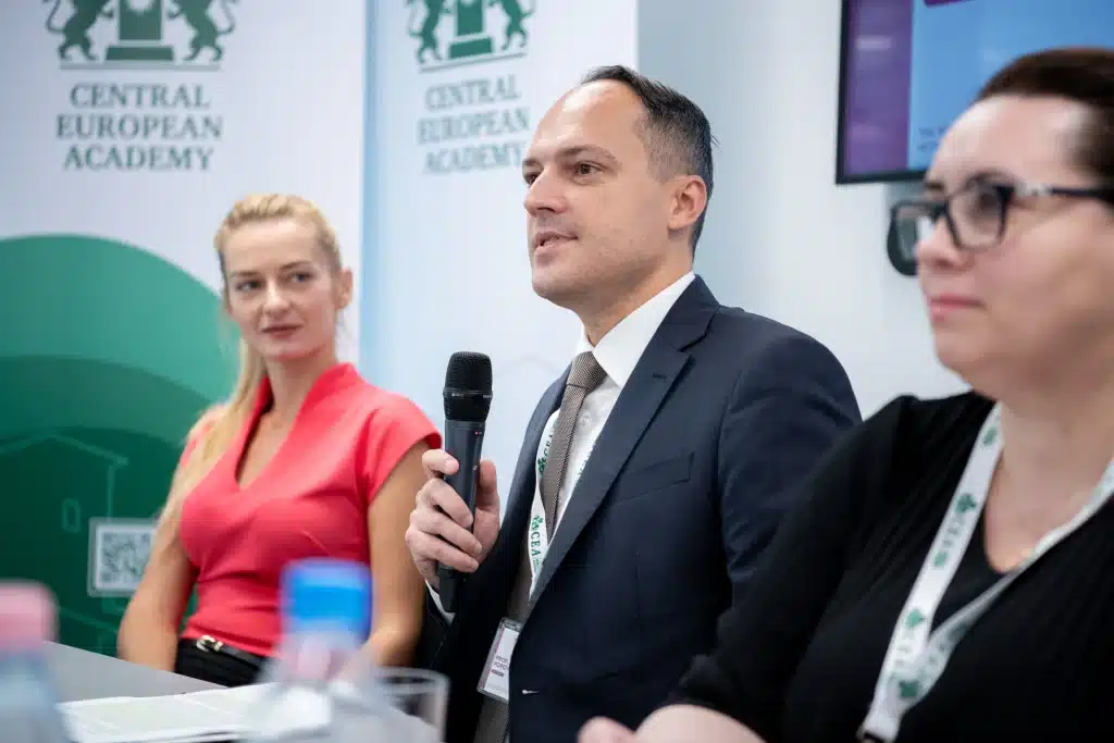 Férfi előadó beszél a CEA pódiumán, hallgatóság előtt