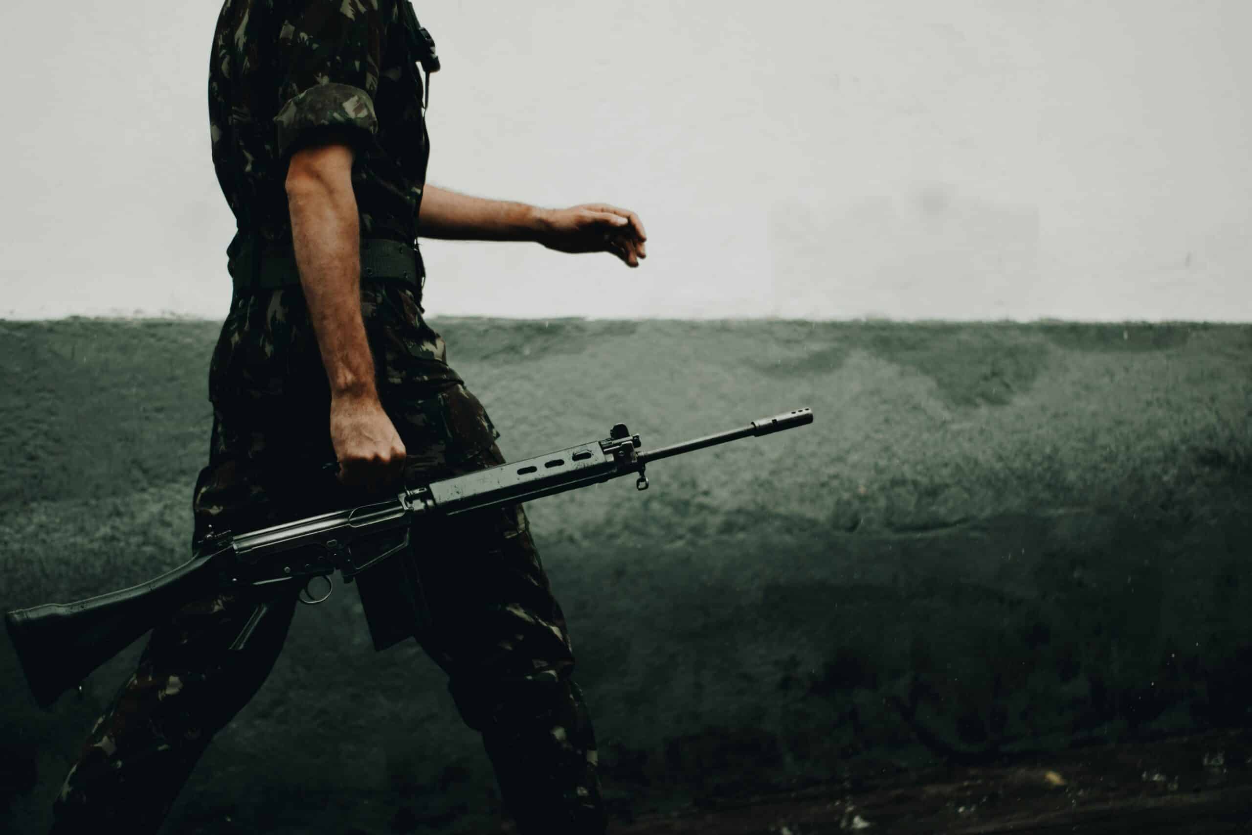 Silhouette of a soldier with a weapon against a sunset sky
