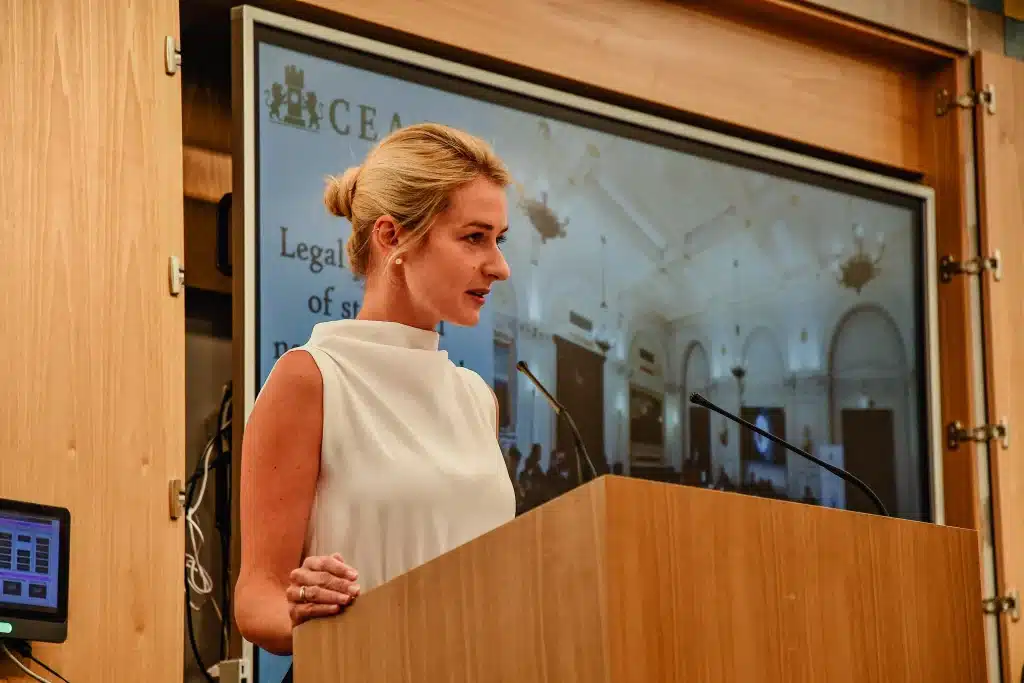 Female speaker at the podium with a screen in the background