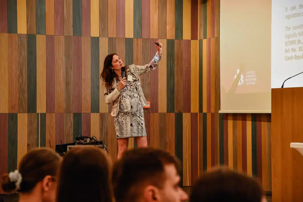 Female speaker giving a presentation in front of a screen