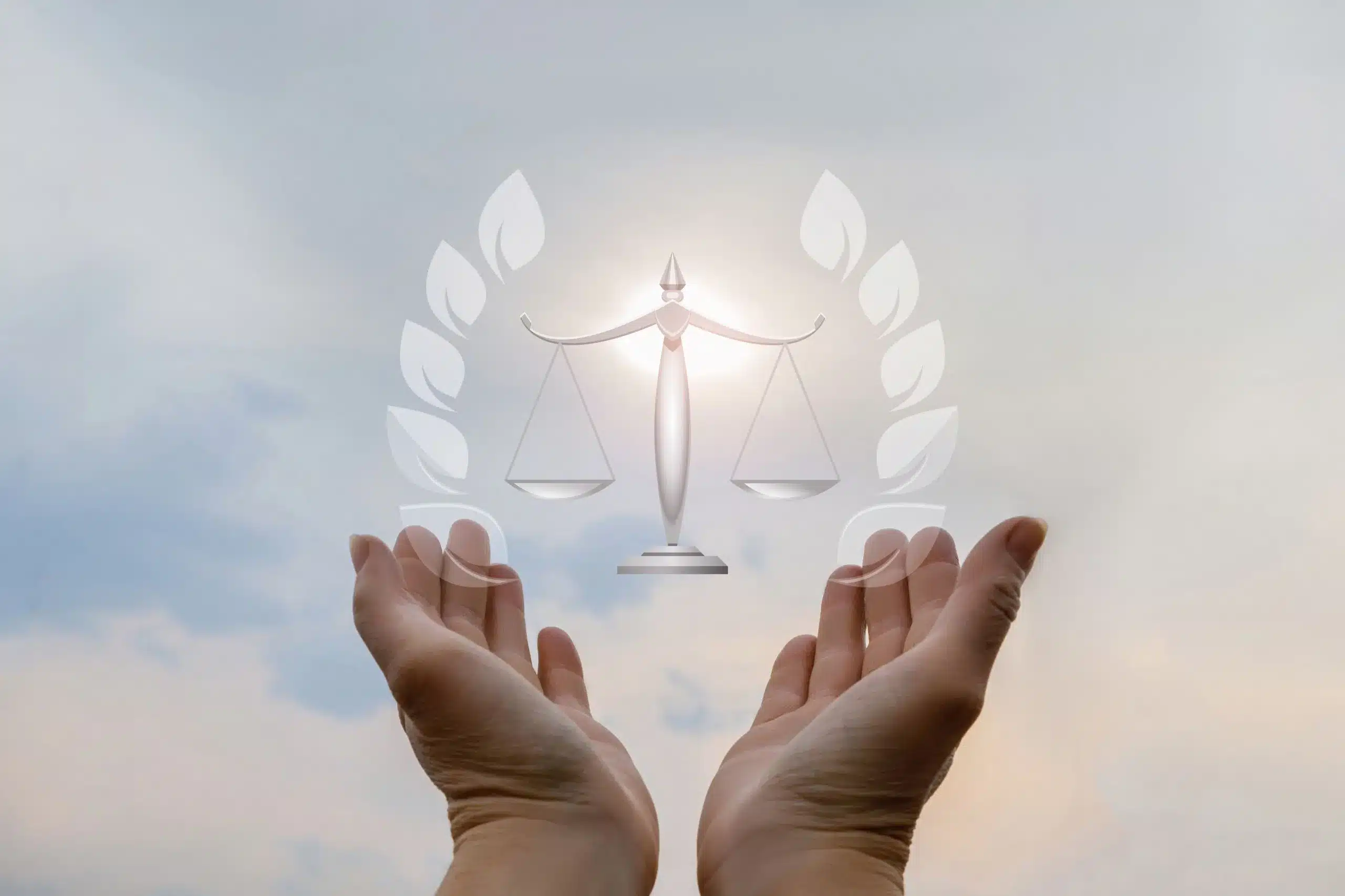 Two hands holding the symbol of scales against a sky background.