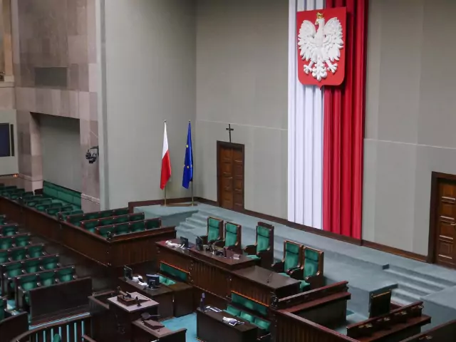 Parlament ülésterme nemzeti zászlókkal és címerekkel.