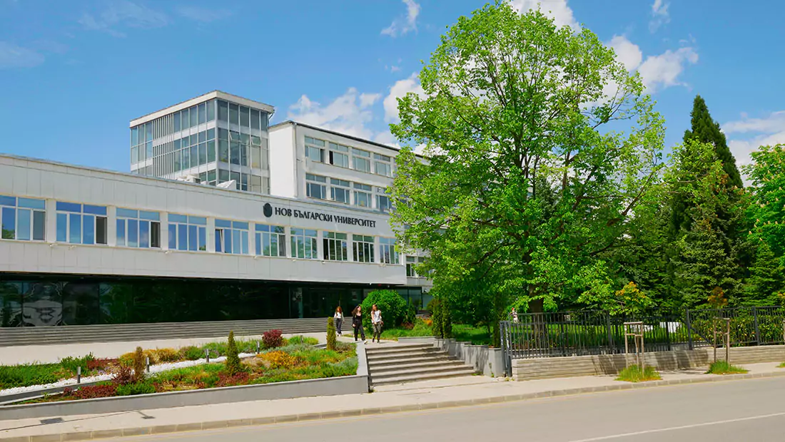 Modern university building with a glass façade and trees.