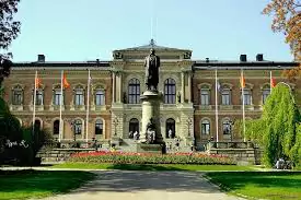 Historic university building with a statue and national flags in front of the entrance