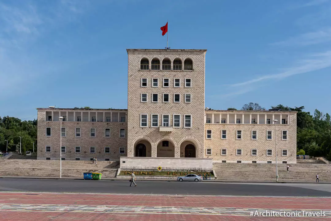 Monumental stone university building with a flag.
