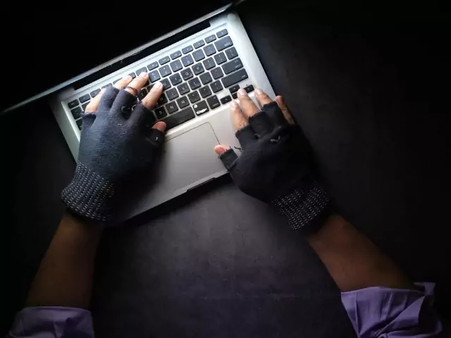 Kesztyűs kéz laptop billentyűzeten gépel