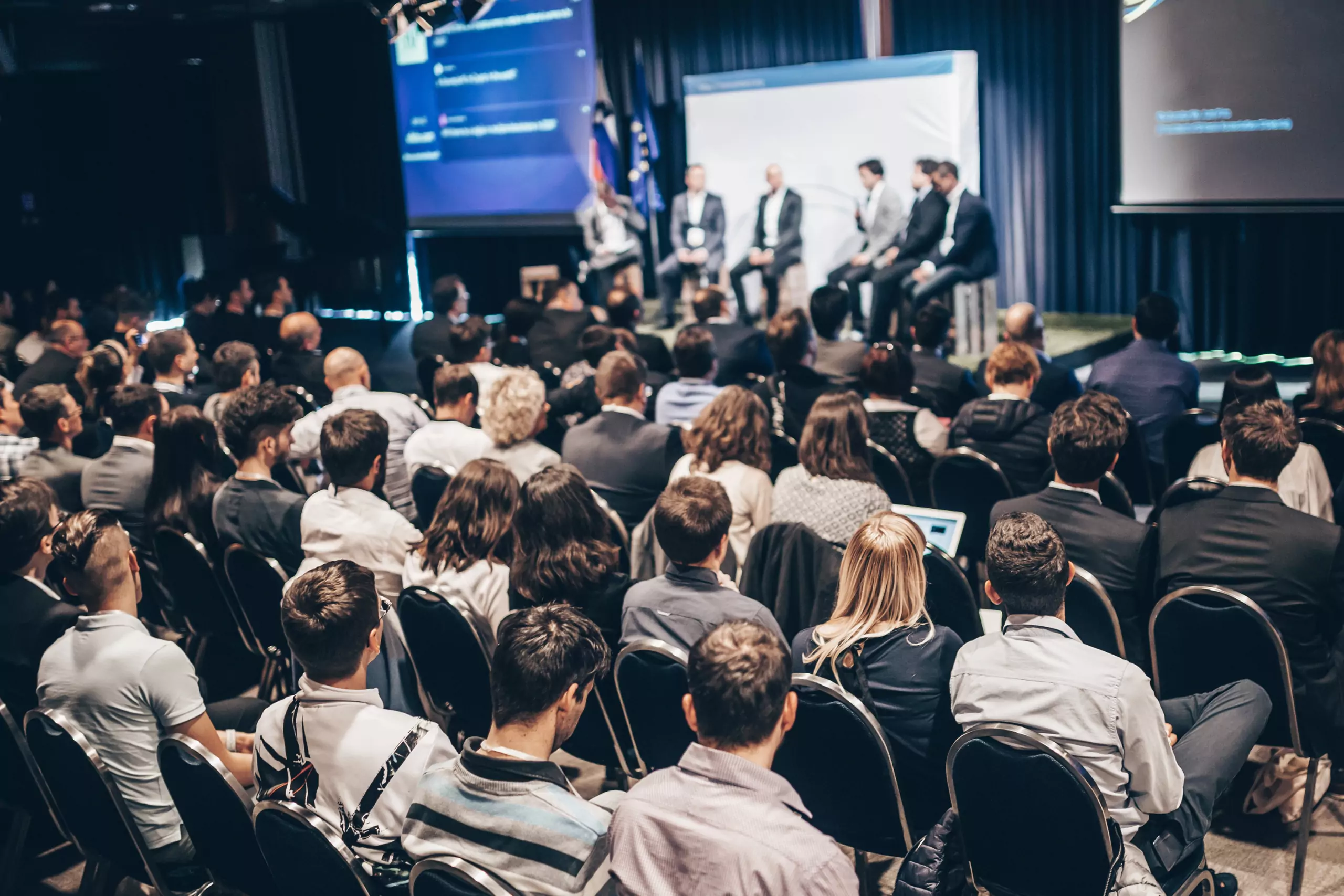 Konferencia közönsége és előadói panel