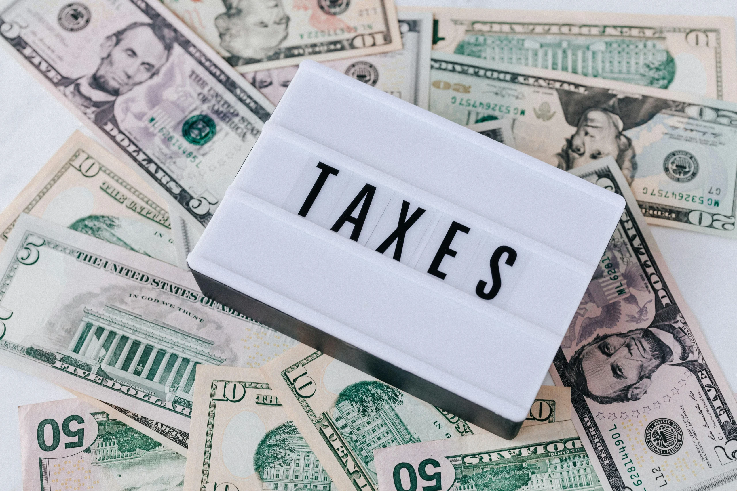 "Taxes" felirat pénzkötegek felett
