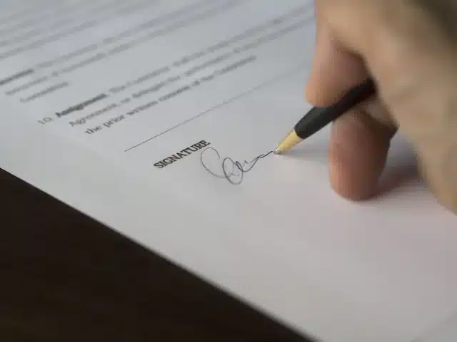 Kéz szerződést ír alá tollal