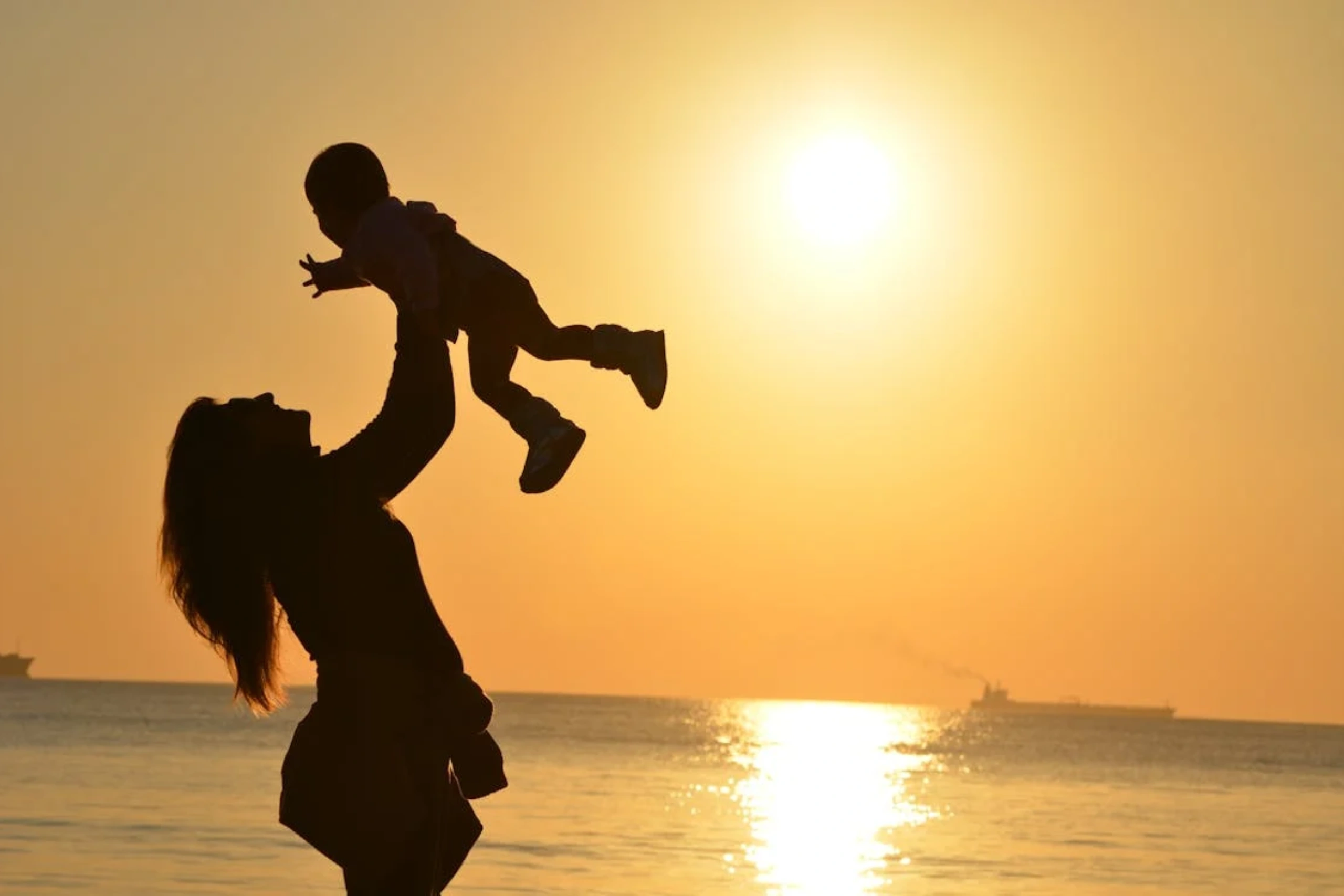 Man lifting his child at sunset on the beach